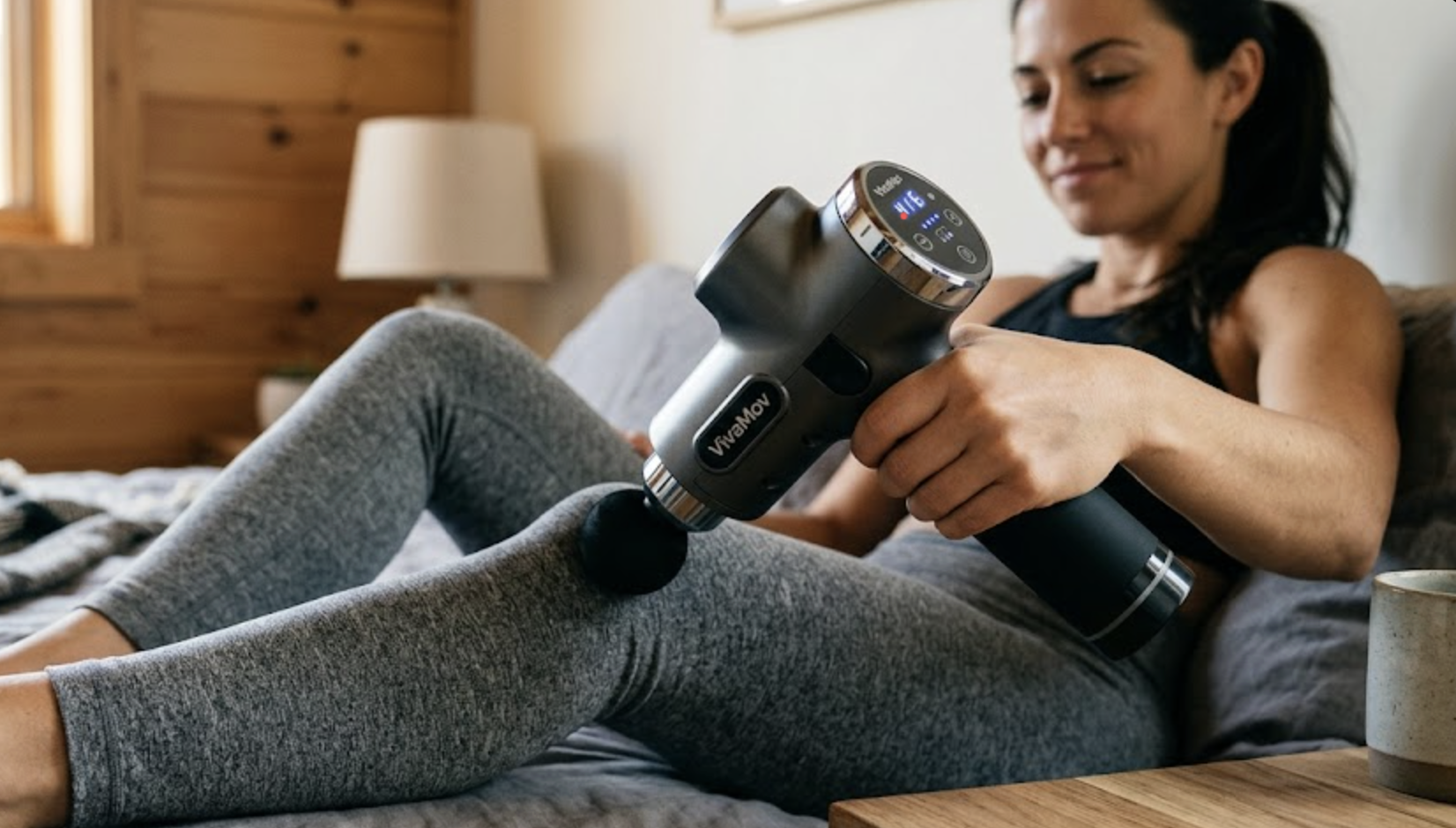 Mulher a utilizar a pistola de massagem VivaMov em casa, para uma rotina de bem-estar e recuperação pessoal.
